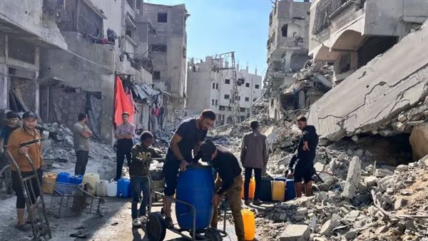 فلسطينيون يملأون حاويات بالمياه النظيفة وسط الدمار