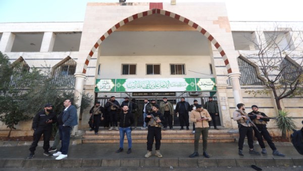 مسلحون يقفون أمام مسجد بسوريا عقب انفجار بحمص